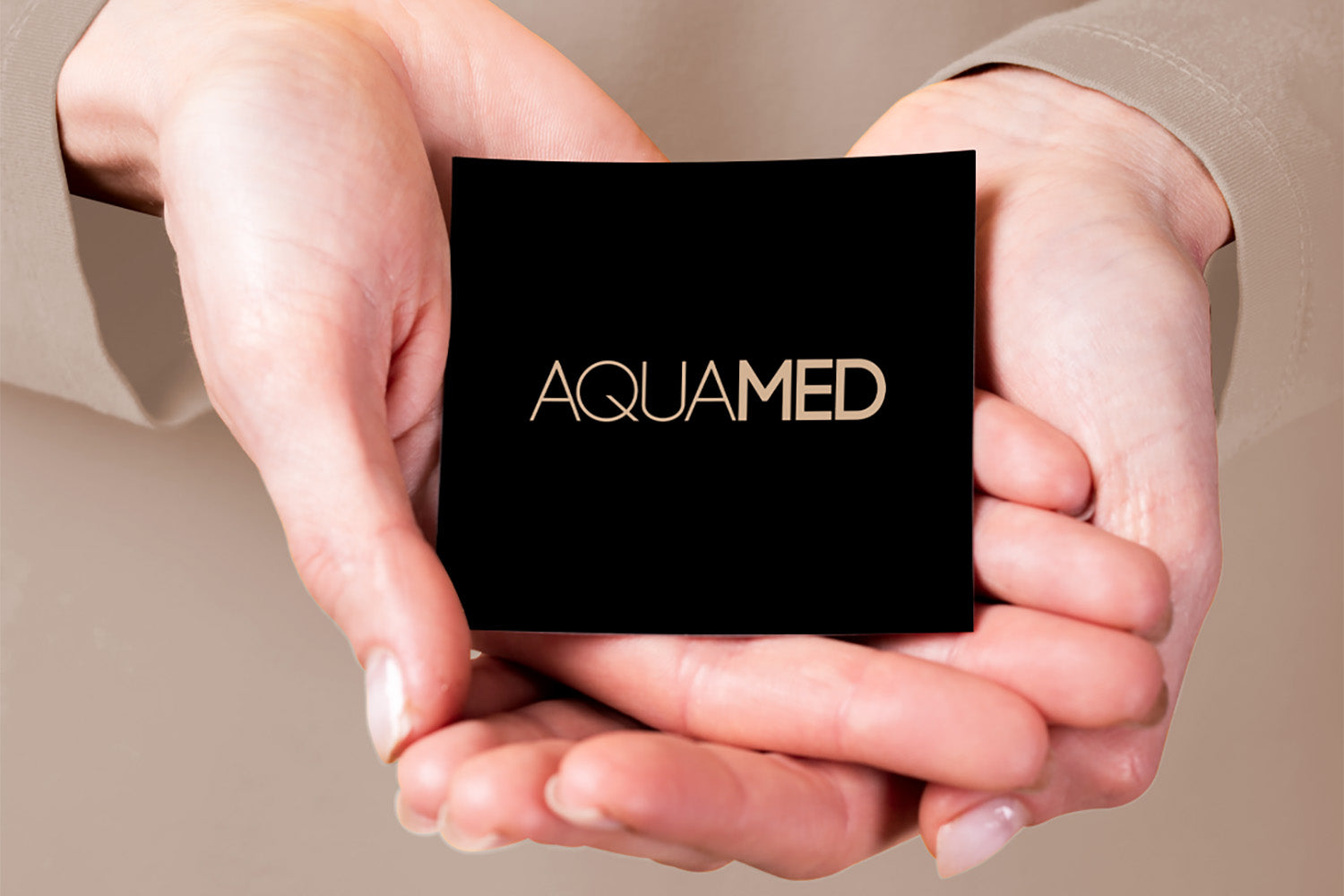 Dos manos sujetan una tarjeta que dice "Aquamed".