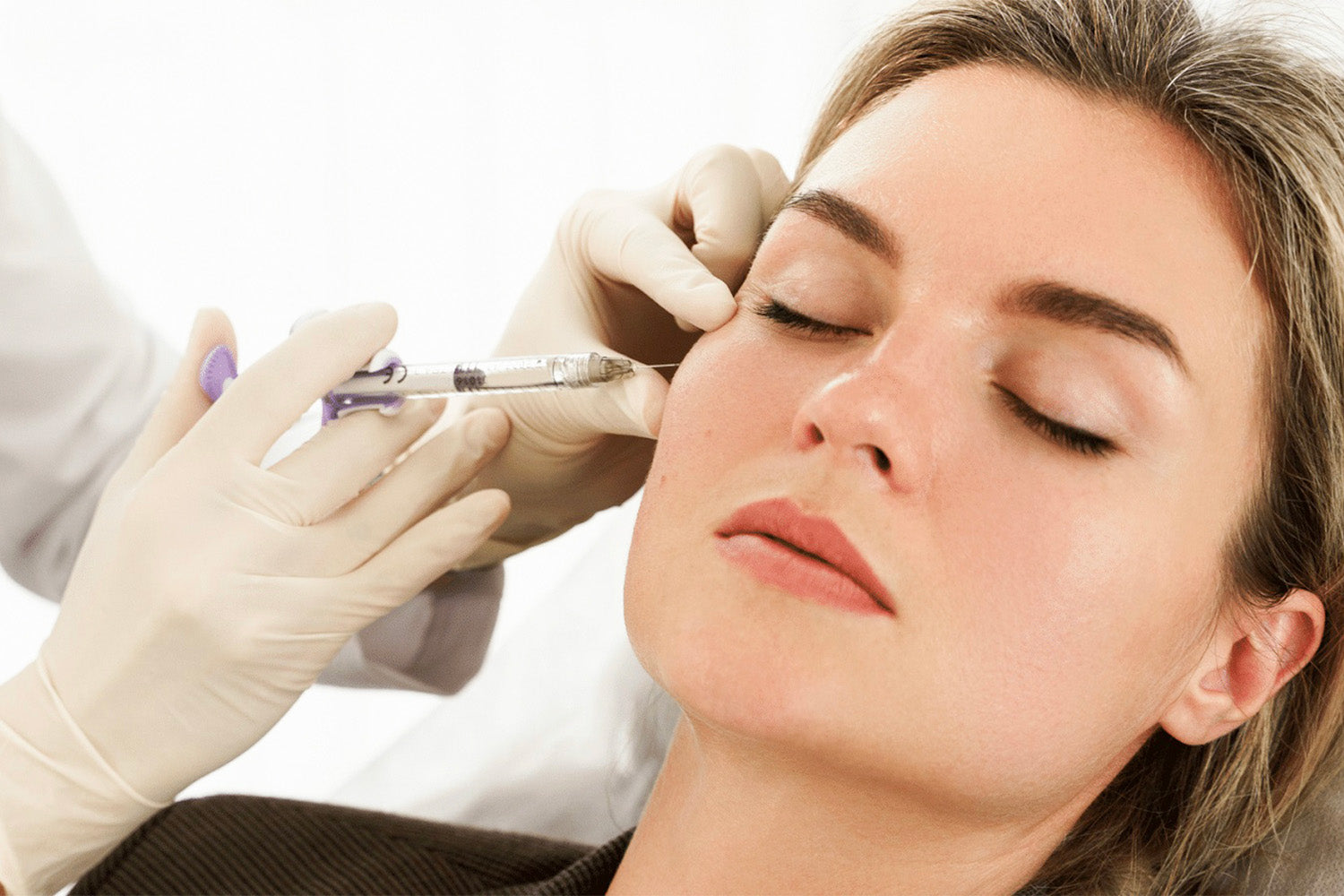 Mujer recibiendo un tratamiento cosmético en el rostro.