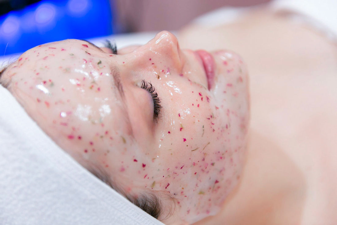 Acercamiento del rostro de una mujer recibiendo un facial de color rosado.