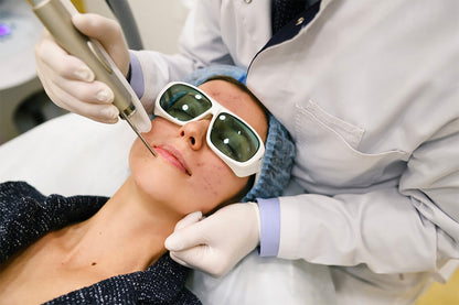 Mujer recibiendo un tratamiento cosmético de láser en el rostro.