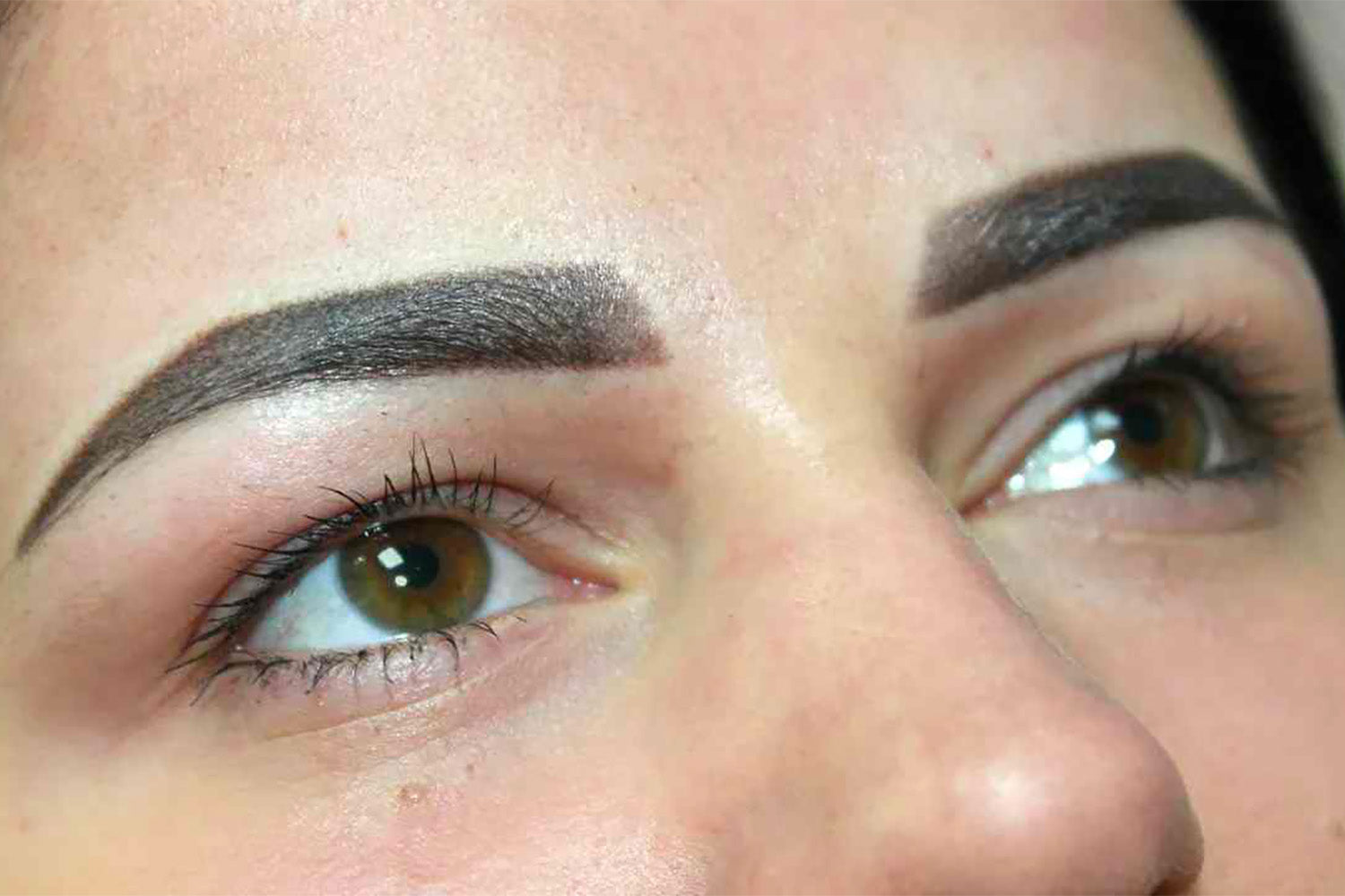 Acercamiento a las cejas de una mujer con un tatuaje facial en las cejas.