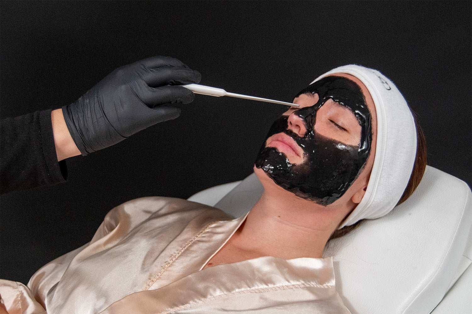 Mujer recibiendo facial de color negro.